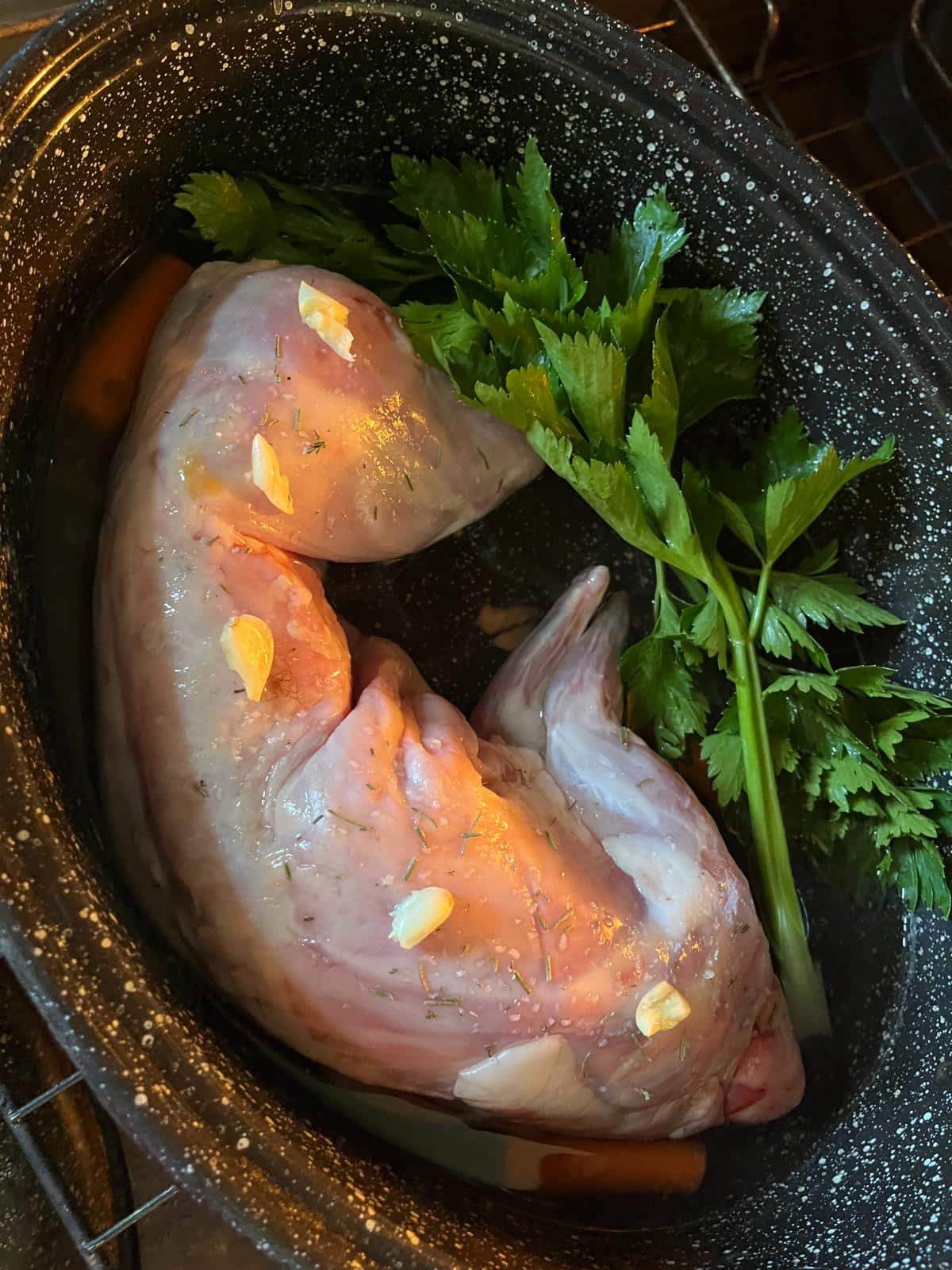 Rosemary and garlic on whole rabbit carcass ready to roast